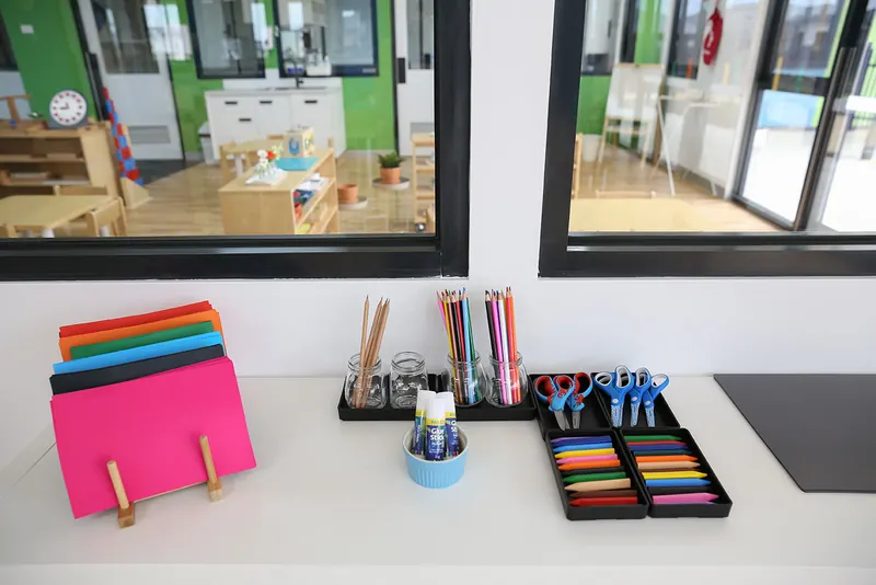 Art shelf with coloured pencils, scissors and paper set out for children to choose