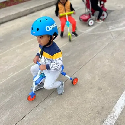 Child in a helmet riding a trike on bike day