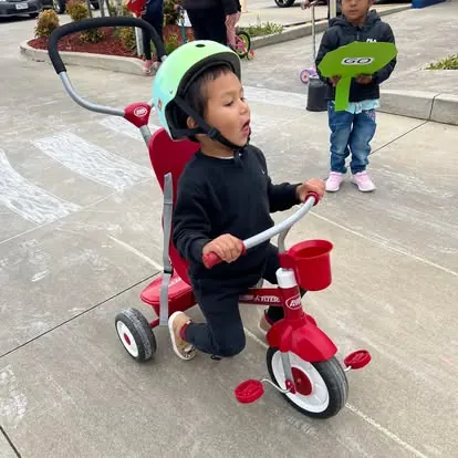 Child riding a red trike during the sport program