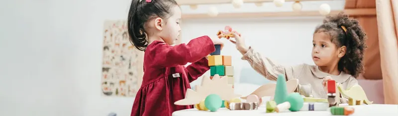 Two young children building together with wooden blocks