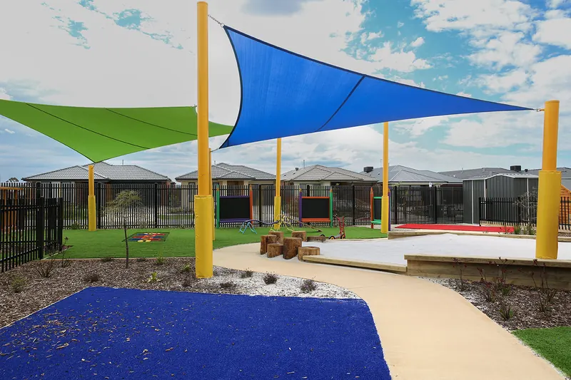 Winding path through the outdoor play space beneath blue and green shade sails
