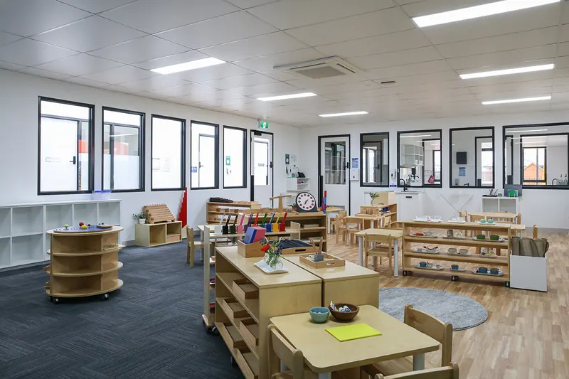 Prepared Montessori environment with open shelves, work tables and floor mats