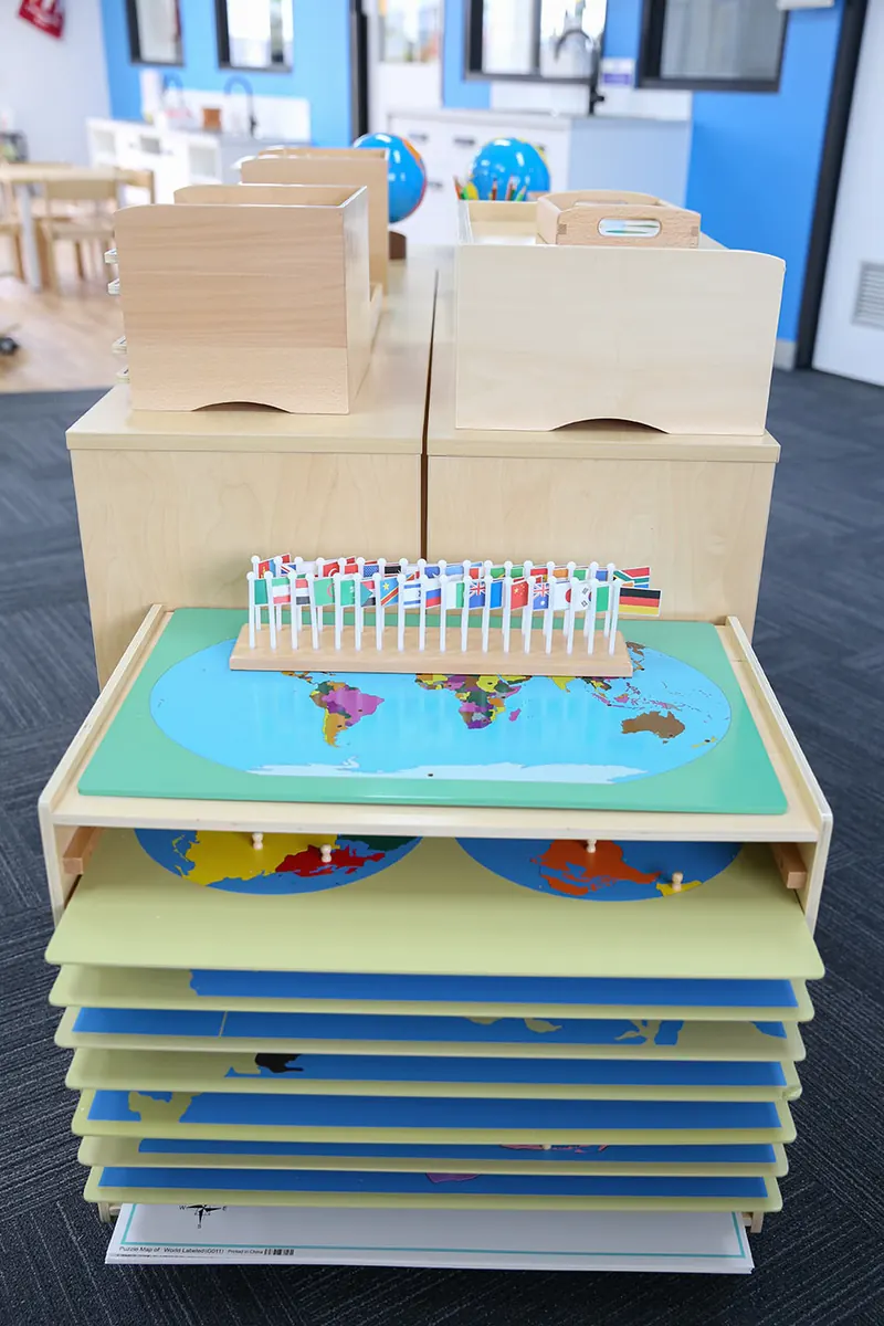 Cabinet of Montessori puzzle maps with a stand of world flags